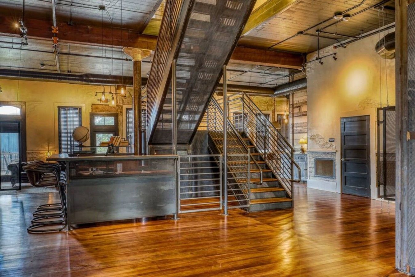 A spacious interior with a central staircase, a bar area, and a fireplace.