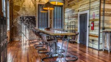 A rustic wooden interior with a long dining table, metal chairs, and pendant lighting.