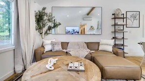 A modern living room with a sofa, a coffee table, and a large mirror. - Modern Rustic Private Ranch w/ Peloton! (Henryville)