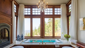 Ein Badezimmer mit großem Fenster, einer Badewanne und zwei Poufs.