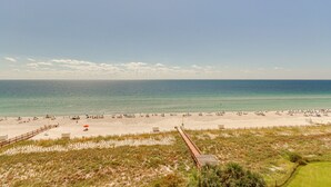 A beach with a wooden boardwalk leading to the shore, sandy beach, and ocean.