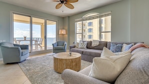 A spacious living room with a large sofa, two armchairs, a coffee table, and a ceiling fan.
