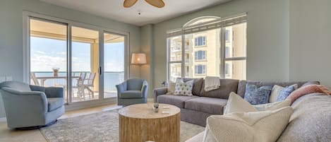 A spacious living room with a large sofa, two armchairs, a coffee table, and a ceiling fan.