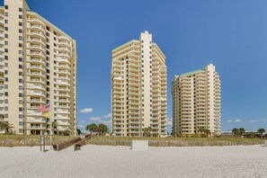 Un hotel sulla spiaggia con diversi edifici a più piani, balconi e una spiaggia sabbiosa.