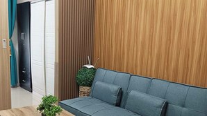 Een moderne woonkamer met een blauwe bank, een houten salontafel en een potplant.