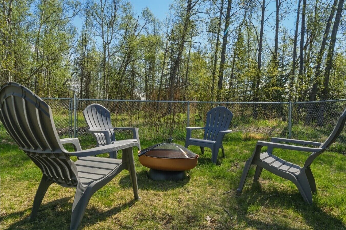 An outdoor seating area with Adirondack chairs and a fire pit.
