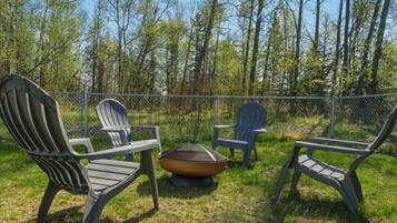 An outdoor seating area with Adirondack chairs and a fire pit.