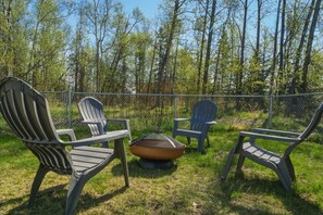 Ein Sitzbereich im Freien mit Adirondack-Stühlen und einem Feuerkorb.