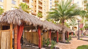 A resort with thatched-roof cabanas, lounge chairs, and palm trees.