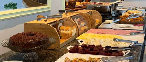 A buffet with various food items, a wooden boat decoration, and a view of the sea through the window.