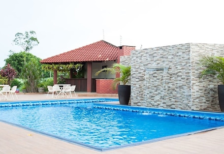 Una piscina al aire libre, sombrillas, sillones reclinables de piscina