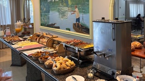 Een buffet met verschillende gerechten, een koffiemachine en een schilderij van een man die aan het vissen is.