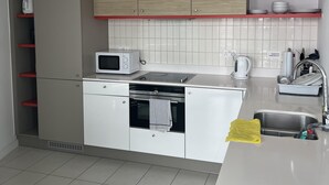 A modern kitchen with white cabinets, a microwave, a kettle, and a sink. - Charming 2-bed Apartment in London (London)