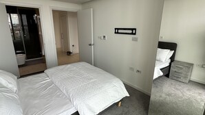A hotel room with a large bed, a small desk, and a mirror. - Charming 2-bed Apartment in London (London)