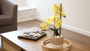Et træsofabord med et brætspil, en vase med gule blomster og en brun stol i baggrunden.