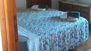Un dormitorio con cama, armario de madera y mesita de noche.