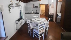 Un comedor con una mesa y sillas, una cocina con armarios blancos y un piso de baldosas.
