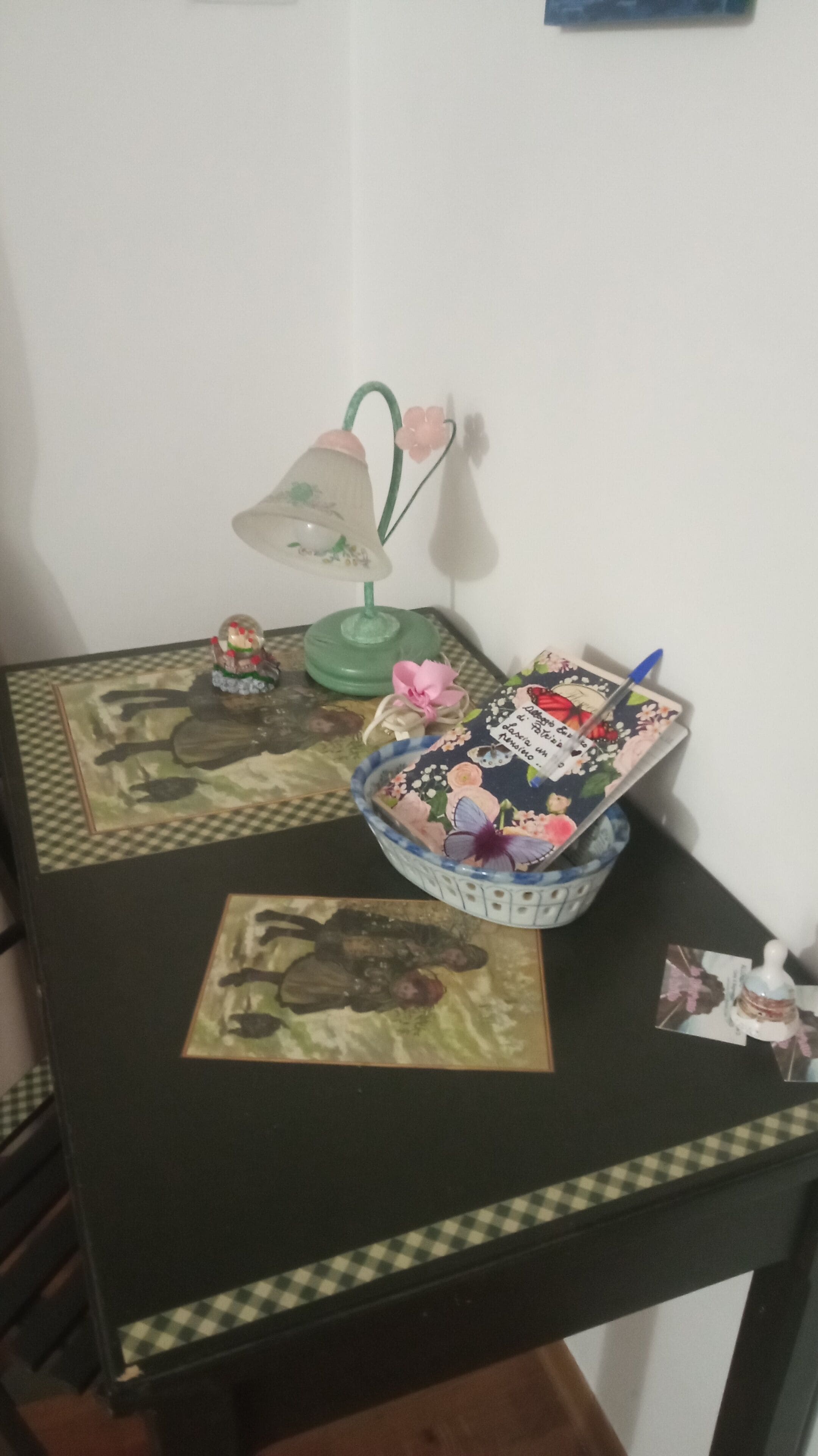 A dining table with a checkered tablecloth, a green lamp, a decorative bowl, and a framed picture.