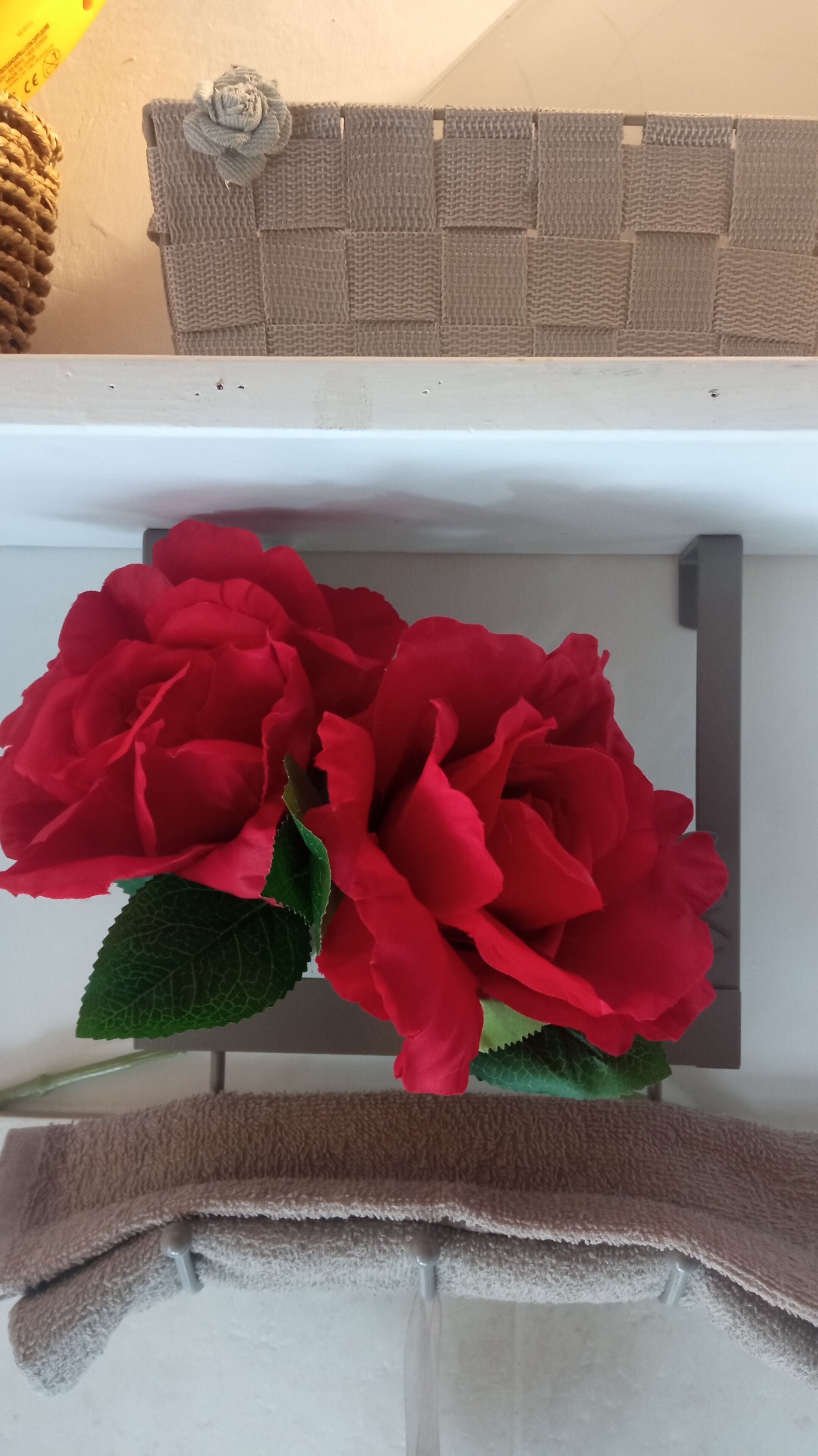 A bouquet of red roses placed on a shelf with a beige towel underneath.