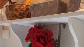 Un baño con una bañera blanca, un perchero con una rosa roja y una toalla decorativa.