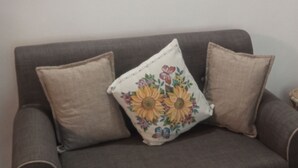 Un sofá gris con dos cojines color beige y una almohada estampada.