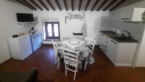 Cocina compacta con comedor, televisor en la pared y ventana con vistas.