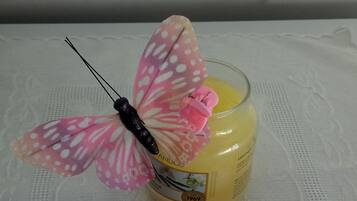A candle with a pink butterfly decoration on a lace tablecloth.