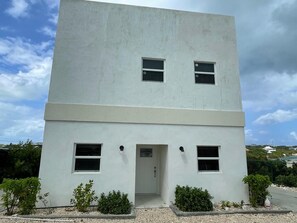 A modern two-story building with a flat facade, two windows on the upper floor, and a door on the lower floor.