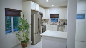 Una cocina moderna con armarios blancos, electrodomésticos de acero inoxidable y una isla central.