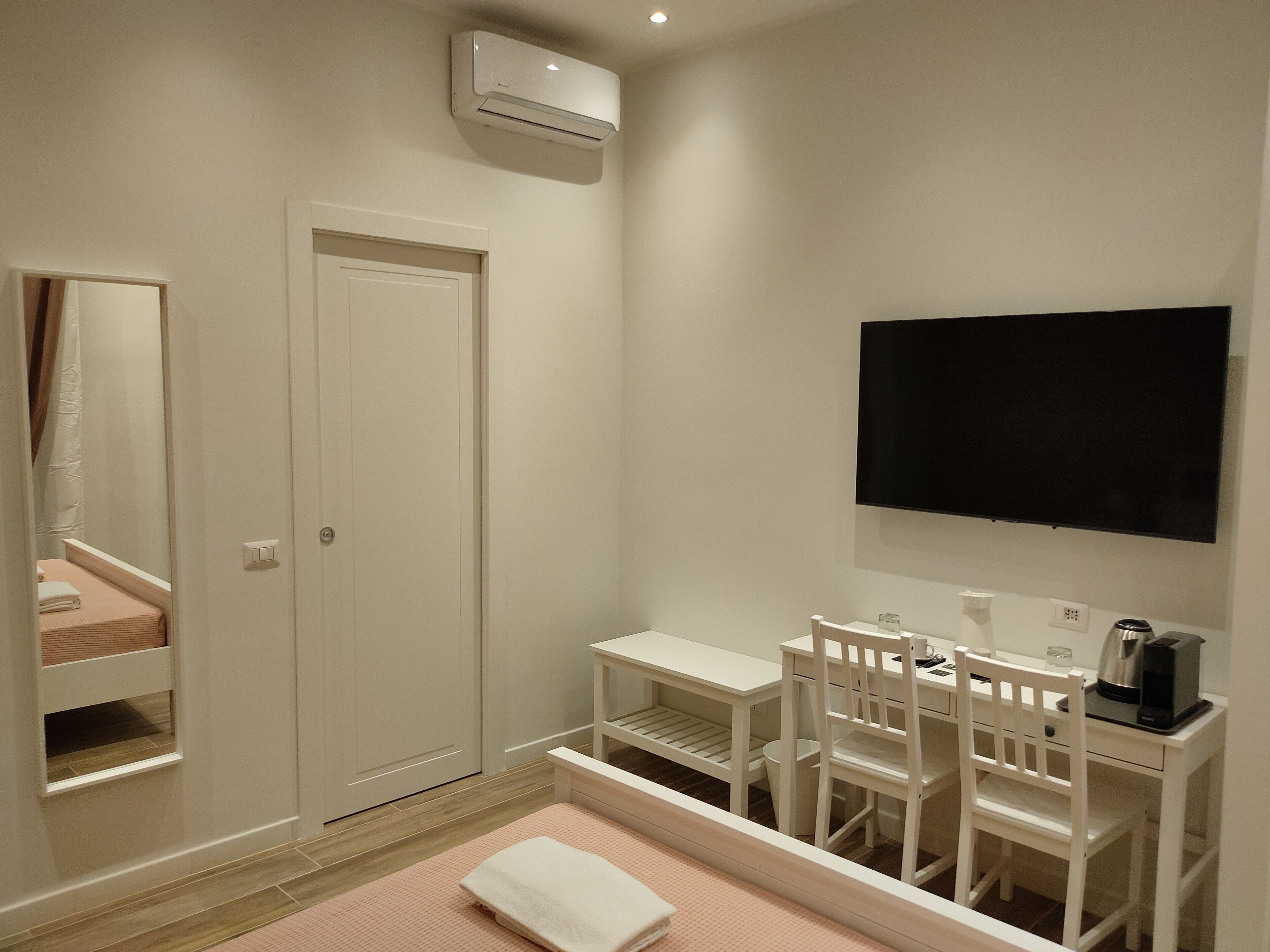 Camera d'albergo con un letto, una scrivania con sedia, una televisione e un condizionatore d'aria.