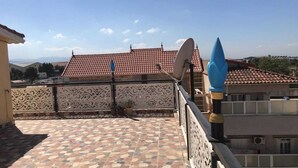 A rooftop terrace with a tiled floor, satellite dishes, and decorative metal railings.