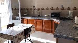 A kitchen with a granite countertop, wooden cabinets, a microwave, and a coffee maker.