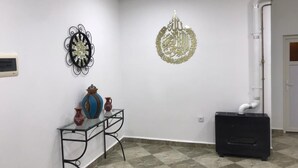 A room with a tiled floor, a black radiator, a decorative metal wall piece, and a wall-mounted air conditioning unit.