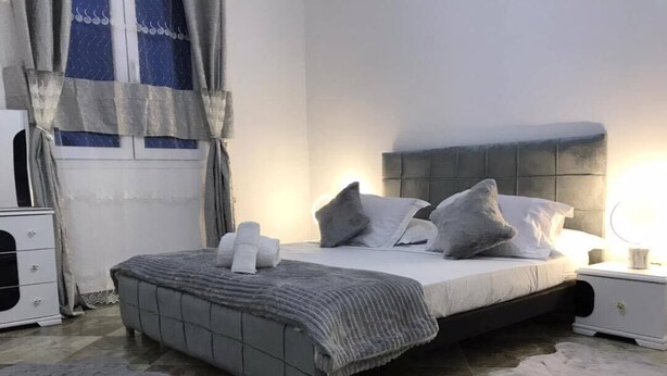 A bedroom with a bed, nightstands, a dresser, and a window with curtains.