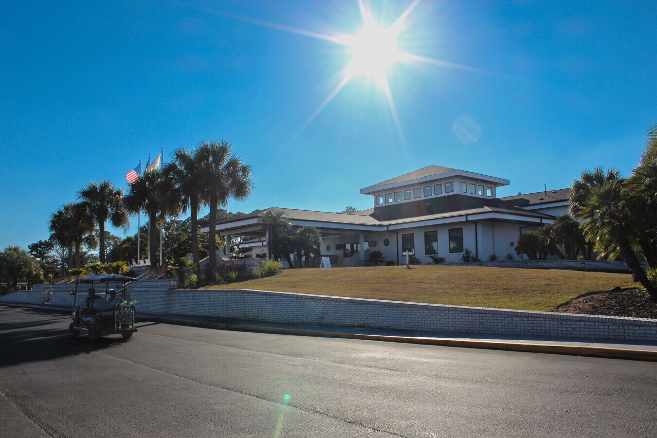 A modern building with a flat roof, large windows, and a paved driveway.