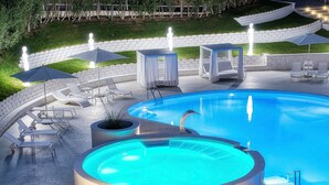 Una piscina con sillas de descanso y sombrillas, rodeada de un muro de ladrillo y follaje.