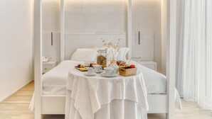 Un dormitorio moderno con una cama bien hecha, una mesita de noche con un teléfono y un servicio de desayuno sobre la cama.