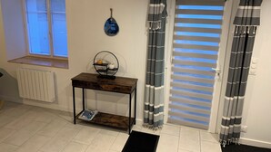 A room with a window, a radiator, a small table with a decorative item, and striped curtains.