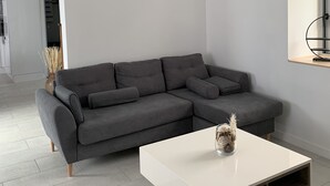 A modern living room with a grey sectional sofa, a white coffee table, and a unique hanging light fixture.