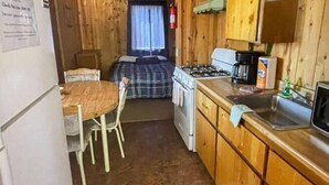 Una cocina compacta con estufa, lavamanos y una pequeña mesa de comedor con sillas.