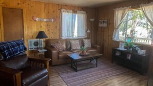 Una habitación acogedora con un sofá de cuero marrón, una mesita de madera y una ventana con cortinas.