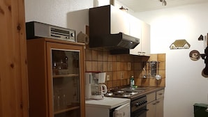 Una cocina compacta con horno integrado, cafetera y lavamanos.