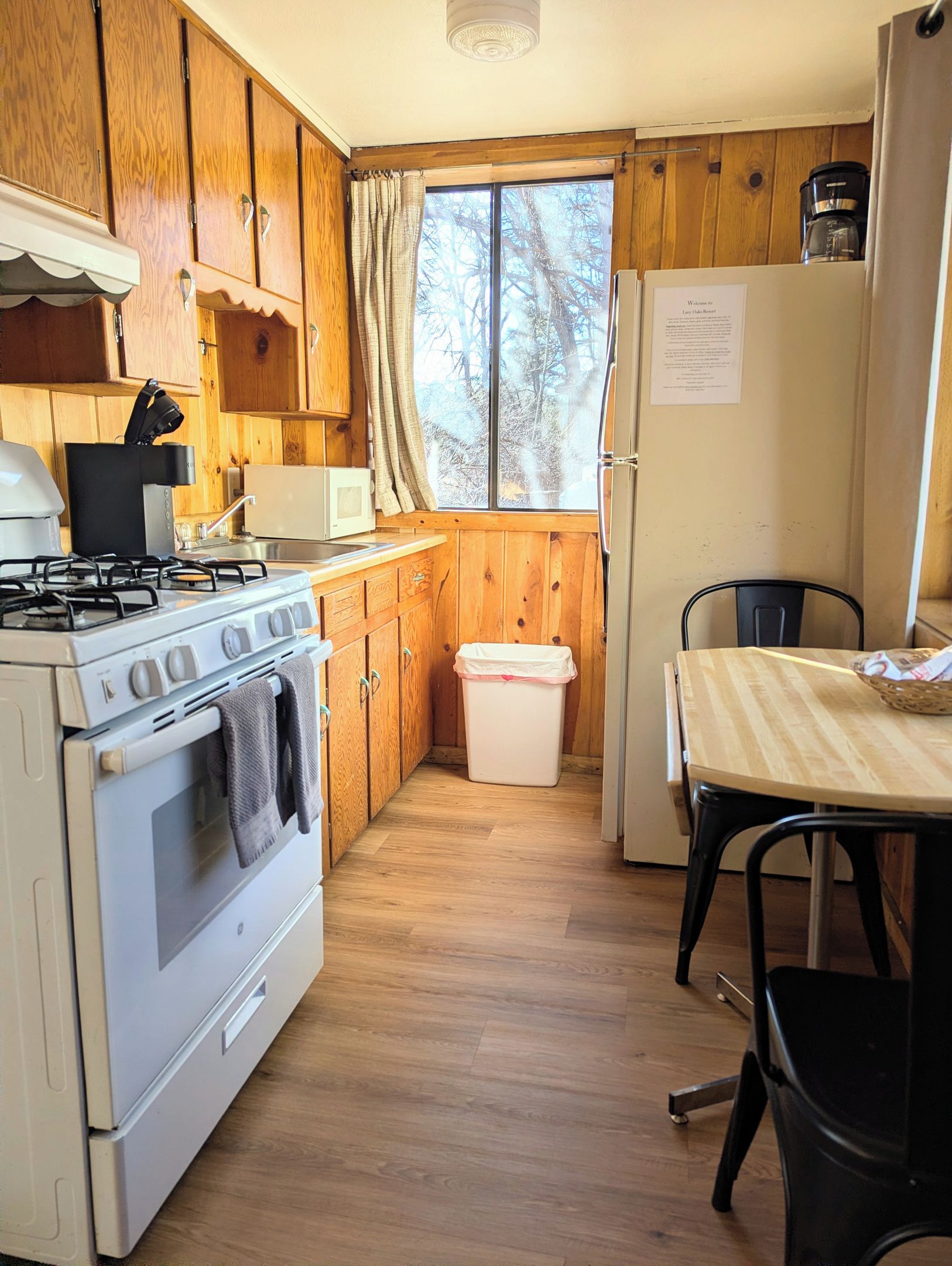 A compact kitchen with wooden cabinets, a stove, a microwave, and a refrigerator.