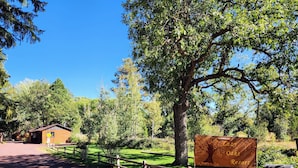 Une enseigne indiquant le complexe hôtelier Oaks Resort, avec une clôture en bois et un chemin de terre menant à un chalet.