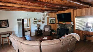 Un salon chaleureux avec un plafond en bois, une cheminée, un téléviseur et un canapé.