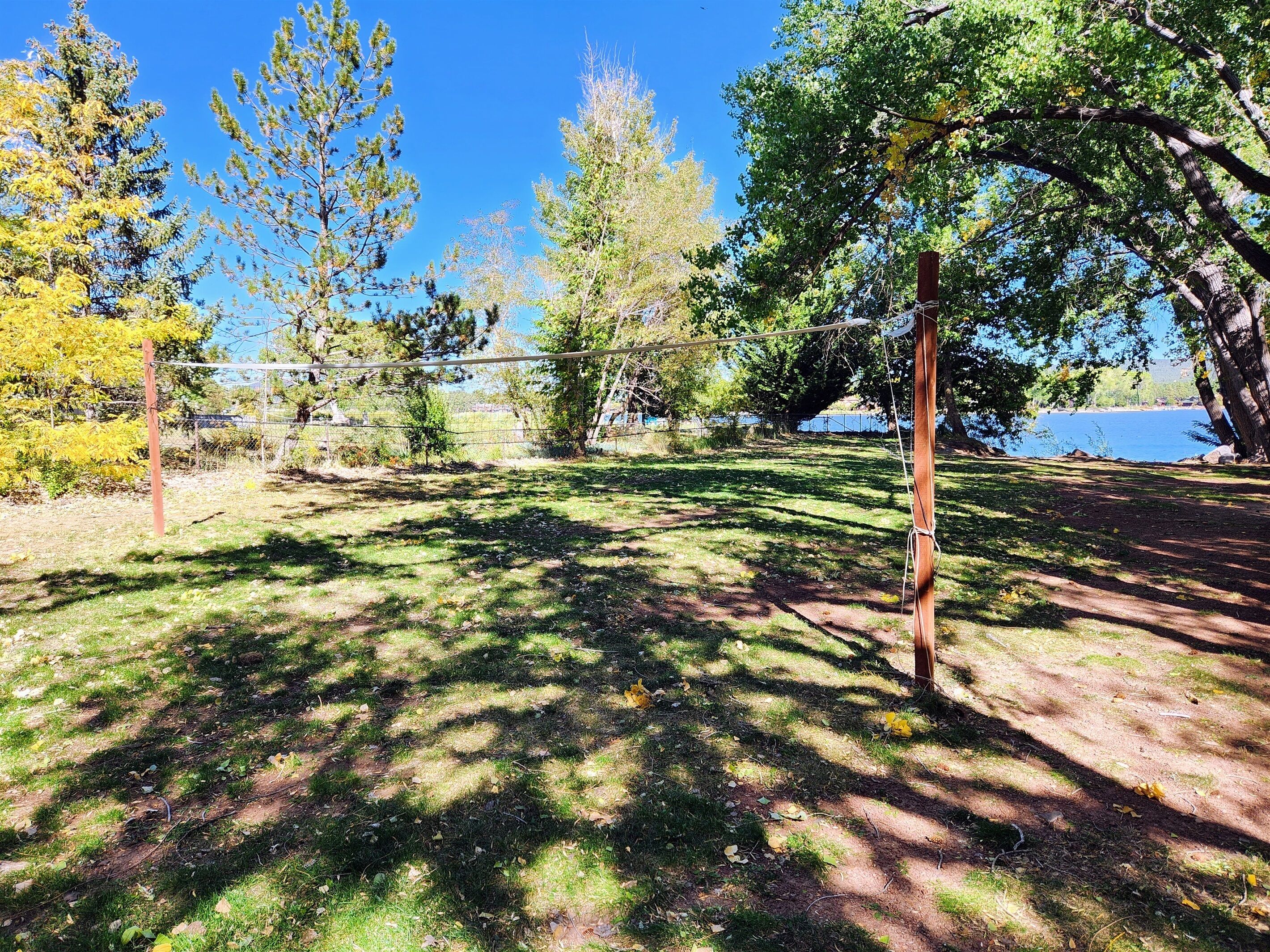 A fenced outdoor area with trees and a clear view of a body of water.