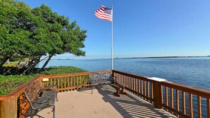 Une terrasse en bois avec un banc en métal et un mât sur lequel flotte un drapeau américain.