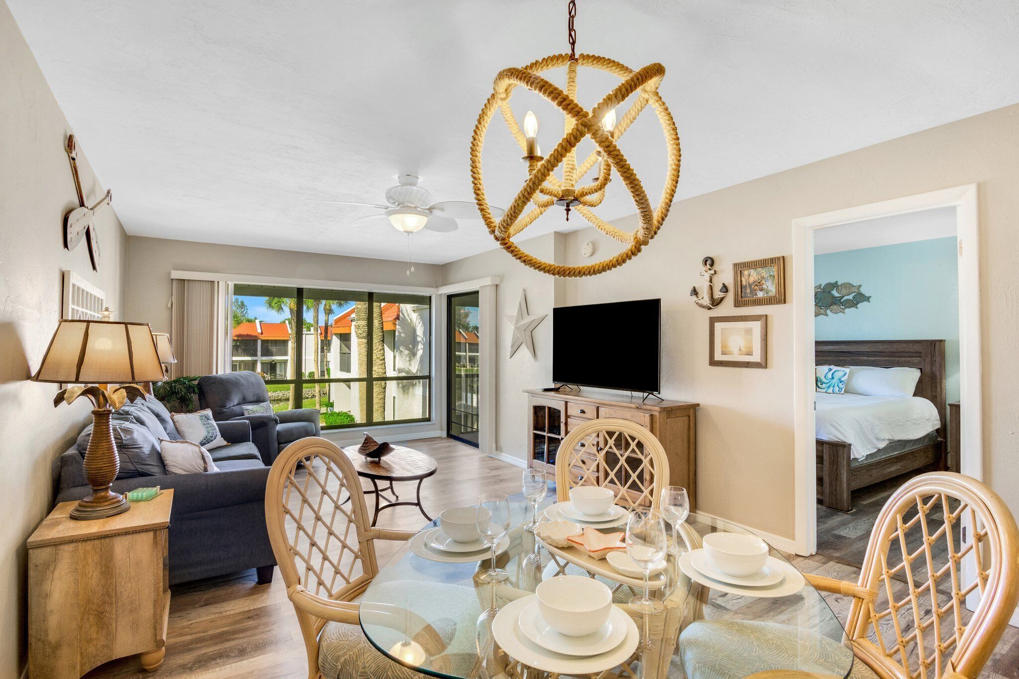 A well-lit living room with a glass dining table, a sofa, and a television.