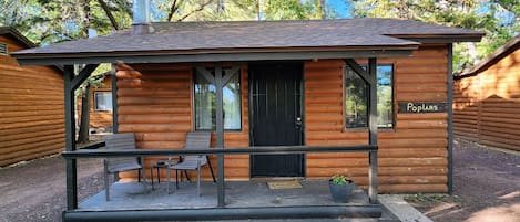 Uma cabana de madeira com varanda, duas janelas e um letreiro escrito 'Poplar's'.