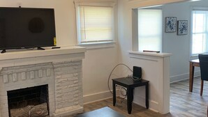 A living room with a fireplace, a television, and a dining area with a table and chairs. - 🏡⭐️Charming 2 bed. historical house -Centrl El Paso
 (El Paso)
